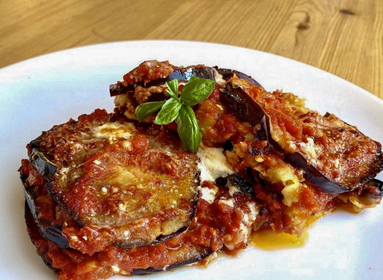 Eggplant Parmigiana with melted mozzarella and tomato sauce, garnished with basil